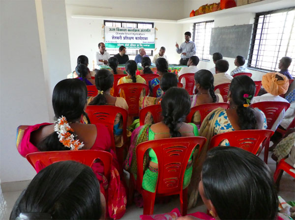 Women participating in an evening training class on ratoon management in Dholgawadi village alongside male farmers.